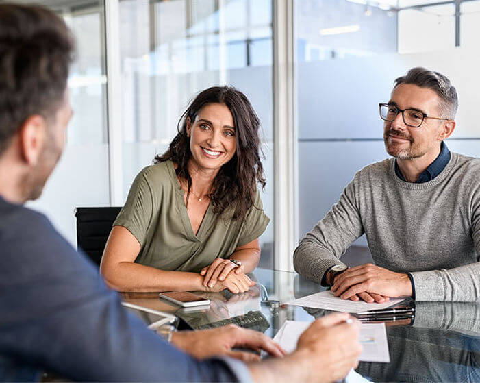 Couple smiling across the table from a Cancer Benefits Center representative