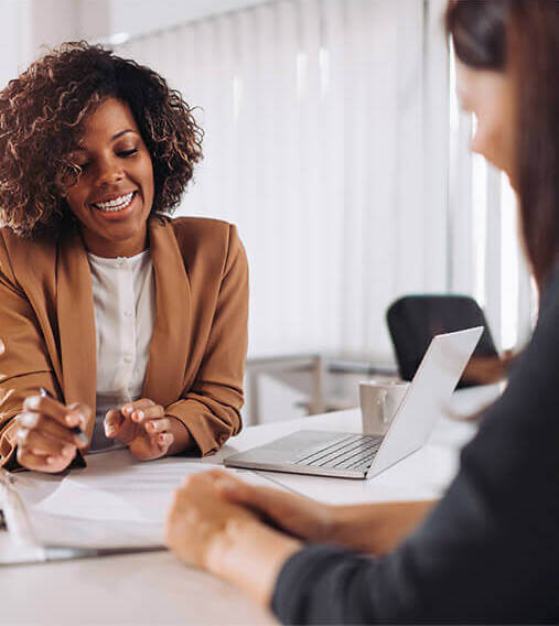 Woman sitting across a desk from a Downwinders® representative smiling and talking.