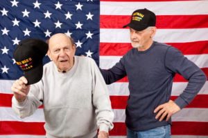 Image of veterans previously exposed to nuclear testing at Bikini Atoll in the Marshall Islands, standing humbly in front of the American flag.