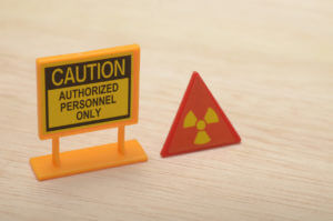 The CAUTION sign and the radiation symbol highlights the potential dangers and the need for restricted access.
